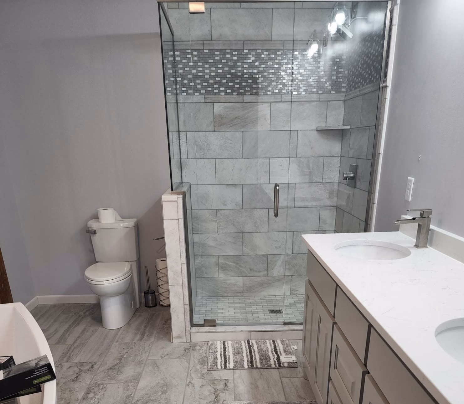 Remodeled bathroom with glass shower enclosure and quartz double vanity