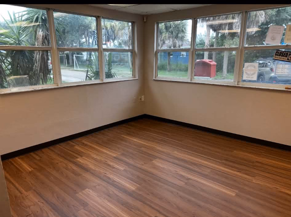 New vinyl plank flooring in a window-lined corner room at Pine Manor, Fort Myers